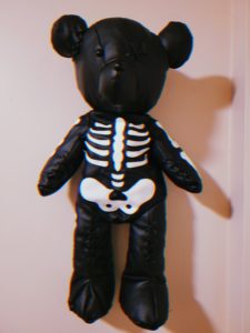 My black teddy bear with a white skeleton hangs on a wall