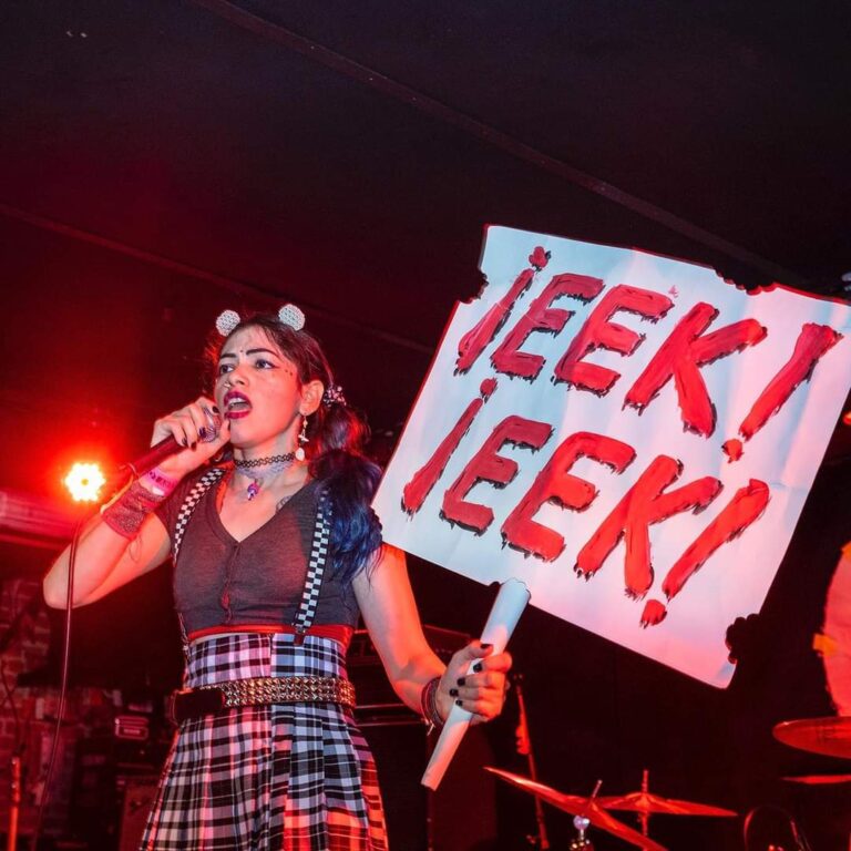 Lead singer of Ratas en Zelo holds up a sign that reads "¡Eek! ¡Eek!"